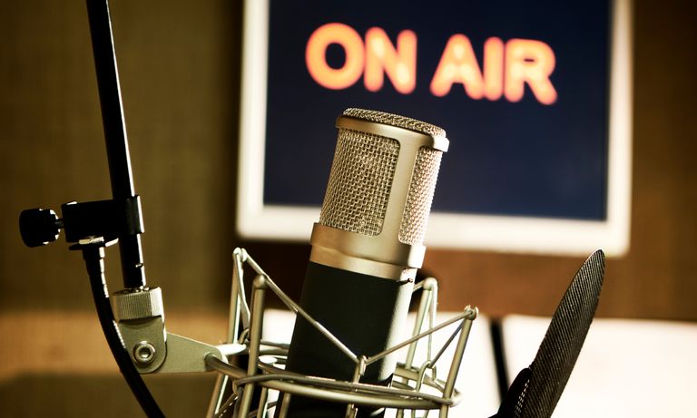 large microphone in front of lit sign reading "on air"