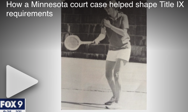 Black and white image of girl in white shorts swinging a wooden tennis racquet